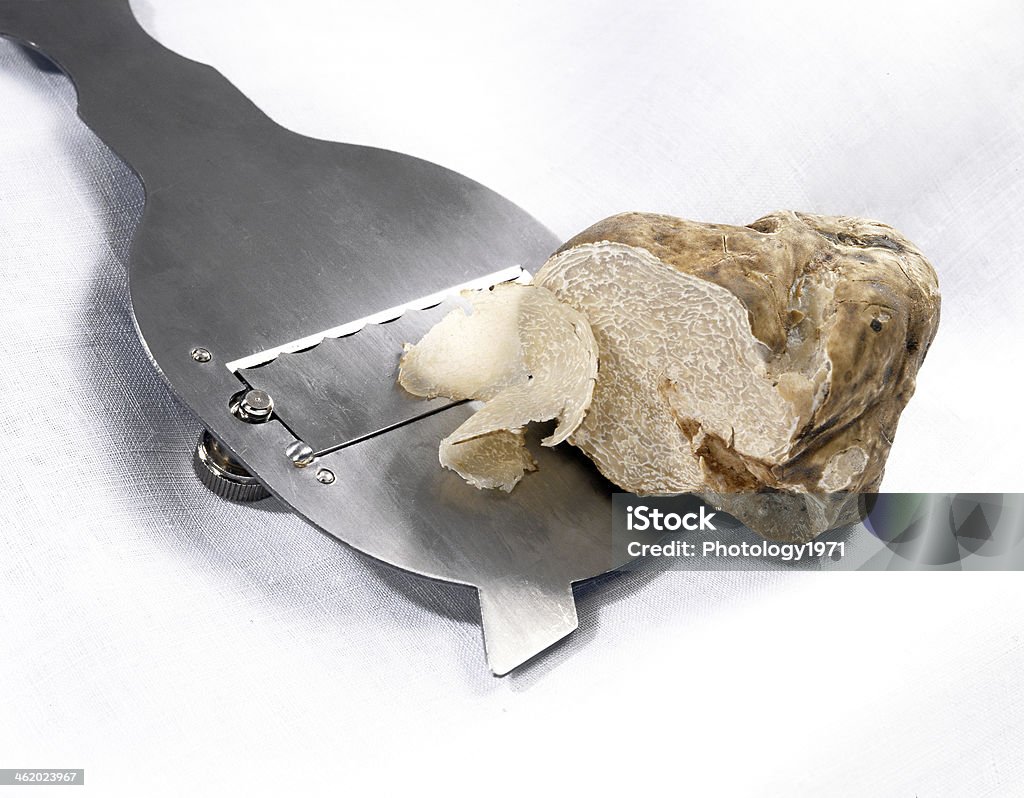 Slicing a white truffle Slicing a white truffle into fine slices with a stainless steel cutter for use as a gourmet ingredient to flavour food in cooking Truffle - Fungus Stock Photo