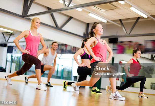 Sonriente Mujer Haciendo Lunges En Un Gimnasio Foto de stock y más banco de imágenes de Aeróbic - Aeróbic, Gimnasio escolar, Gimnasio