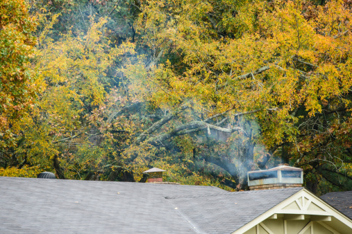 Smoke is coming from a chimney above a house.