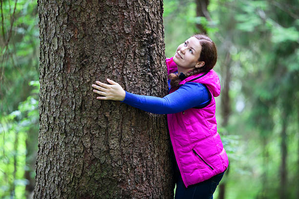 istock Joyful woman embracing pine stem 462037555