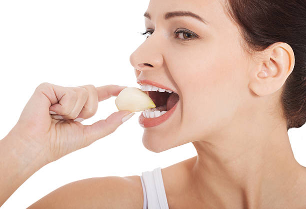 Beautiful woman eating garlic. stock photo