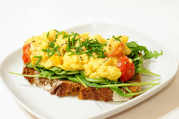 Scrambled Eggs on Rye Bread A healthy breakfast of scrambled eggs on rye bread with tomatoes and arugula. egg cherry tomato rye stock pictures, royalty-free photos & images