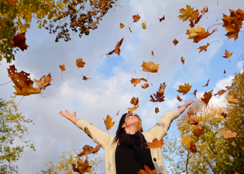 happy woman throwing with autumn leaves