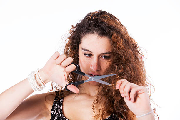 Unhappy woman cutting her hair with a scissor