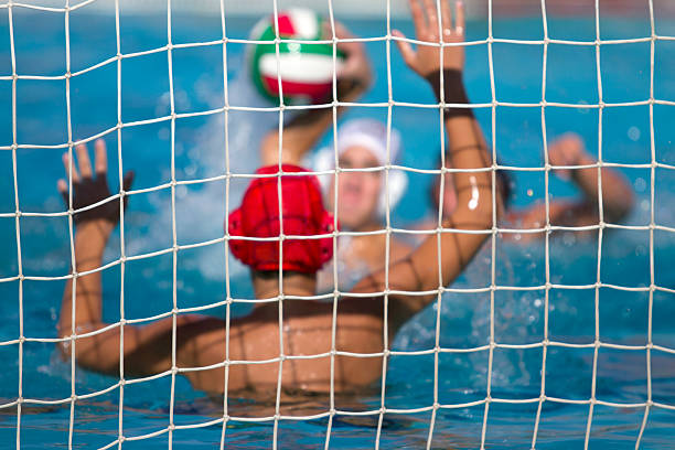 Photo of water polo game taken from behind goal keeper Goalie, Goal water polo cap stock pictures, royalty-free photos & images