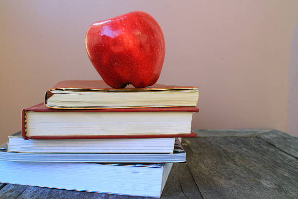 istock teacher's desk with stack of exercise books and apple 462113583