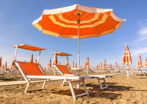 Las sillas reclinables y sombrillas en Rímini playa, italia photo