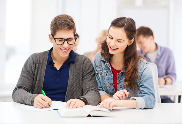 duas adolescentes com notebooks e o livro na escola - learning male studying smiling imagens e fotografias de stock