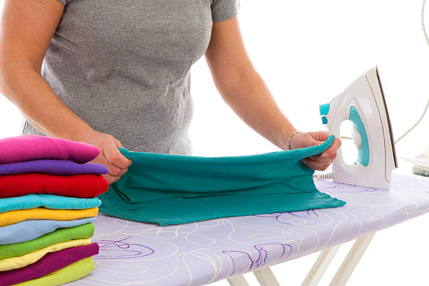 istock housewife is doing the ironing in closeup over white background 462138643