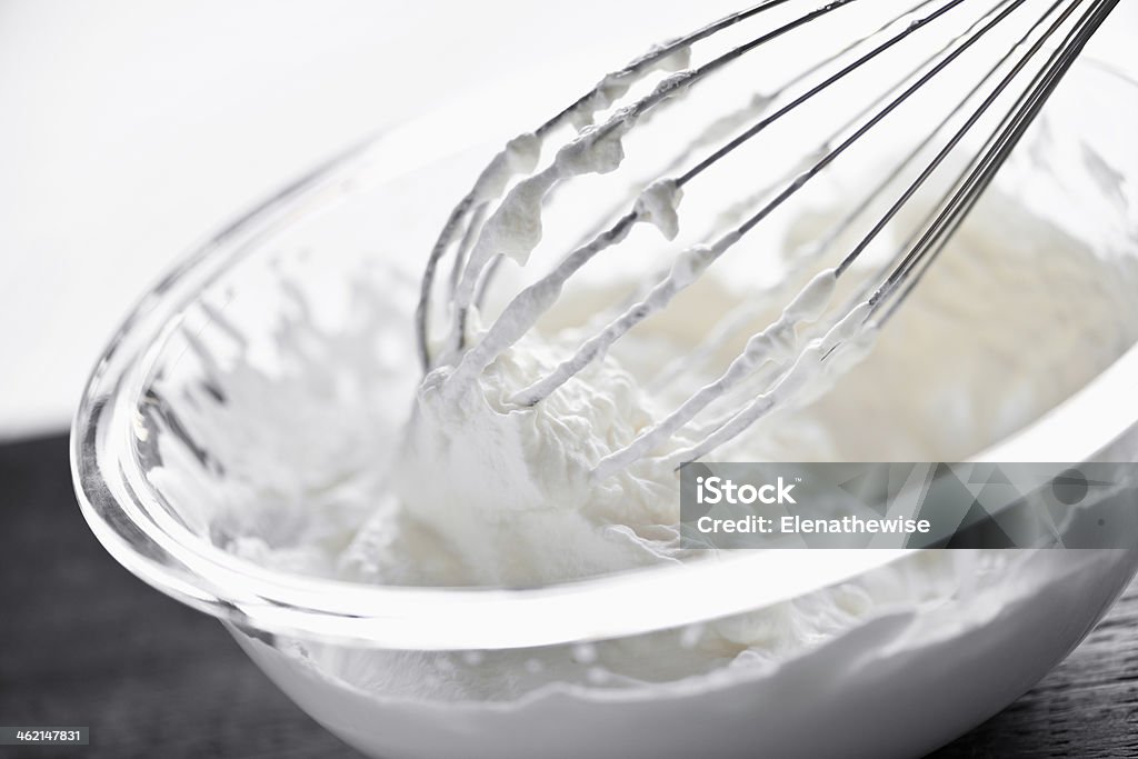 Whisk in whipped cream Closeup of metal whisk whipping cream in glass bowl Baking Stock Photo