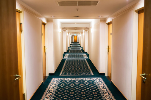Perspective of a hotel hallway with room doors and warm light