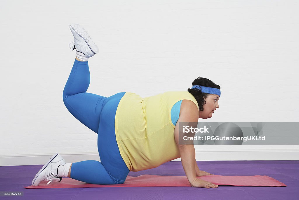 Overweight Woman Doing Aerobic Stretches Full length side view of an overweight woman on floor doing aerobic stretches Adult Stock Photo