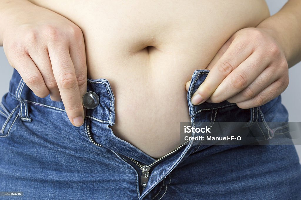 obese mujer tratando de cerrar los botones de sus vaqueros - Foto de stock de Mujeres libre de derechos
