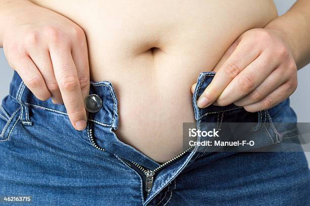 Obese Mujer Tratando De Cerrar Los Botones De Sus Vaqueros Foto de stock y más banco de imágenes de Mujeres