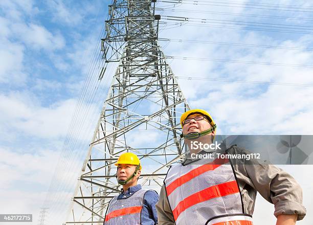 Two Workers Standing Before Electrical Power Tower Stock Photo - Download Image Now - Adult, Asia, Backgrounds