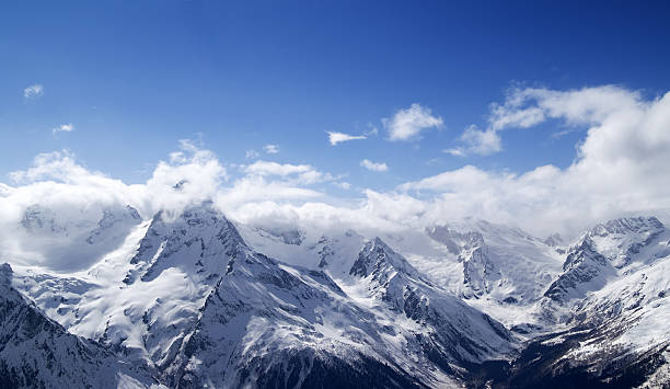 istock Panorama of snowy mountains in clouds 462174047