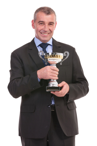 business man holding his trophy and smiling for the camera. on a white background
