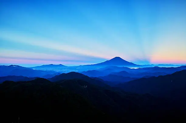 Mt.Fuji shining colors of the rainbow.  It is a landscape from Mt.Touno-dake.  In Japan, it is called "Gokou-ga-sasu" a sight like this. This is very auspicious.  Mt.Fuji is a famous mountain in Japan. It was registered as a World Heritage Site in 2013.