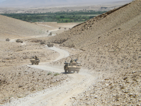 Along dirt track with weapons in mountainous Helmand