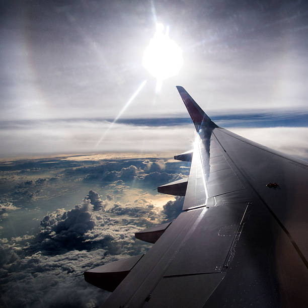 istock Wing of a passenger airplane above the clouds with the sun 462197941