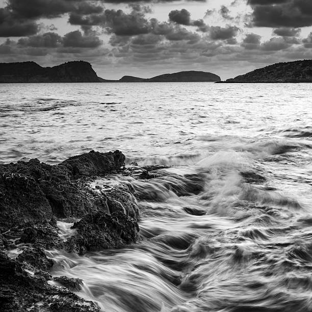 восход солнца над скалистыми береговая линия в черно-белом - black and white landscape square long exposure стоковые фото и изображения