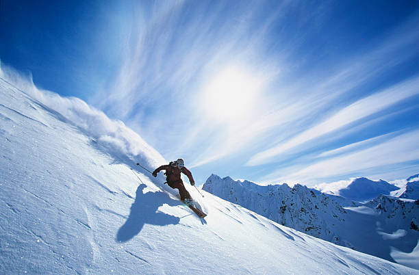 Skier Skiing On Mountain Slope Full length of skier skiing on fresh powder snow extreme sports stock pictures, royalty-free photos & images
