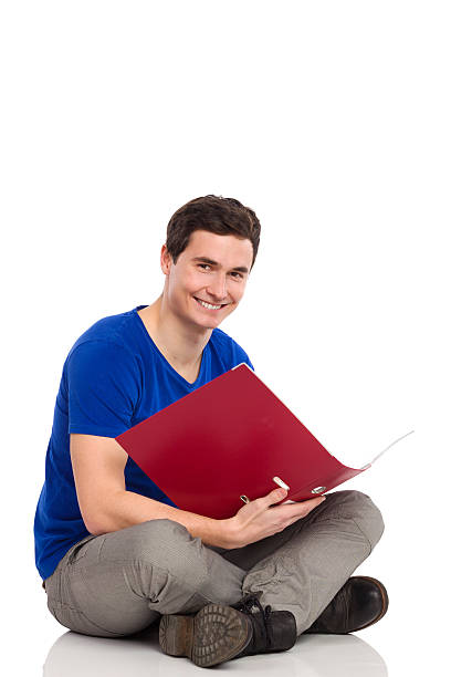 istock Male student with ring binder sitting on floor. 462214959