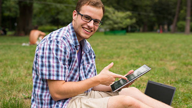 istock Student at the park with tablet sitting on a grass. 462242685