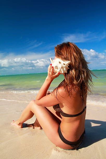 istock Woman listening seashell on beach 462262345
