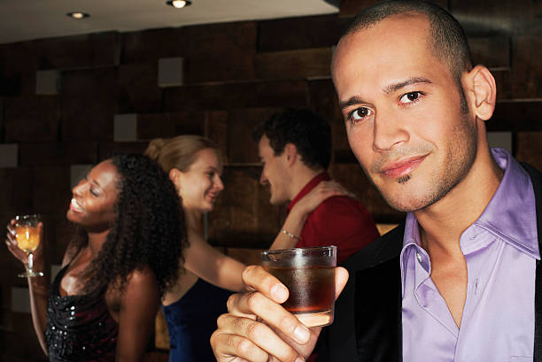 istock Man Holding Drink With People Dancing Behind At Bar 462281667
