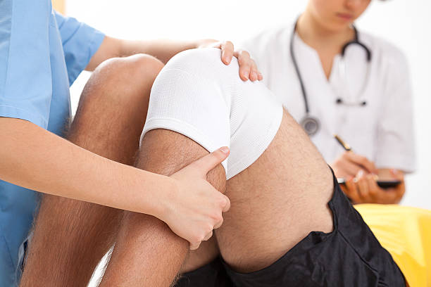 Recovery after knee surgery Doctor supervising the recovery of his patient after knee surgery physical therapy recovery touching human knee stock pictures, royalty-free photos & images