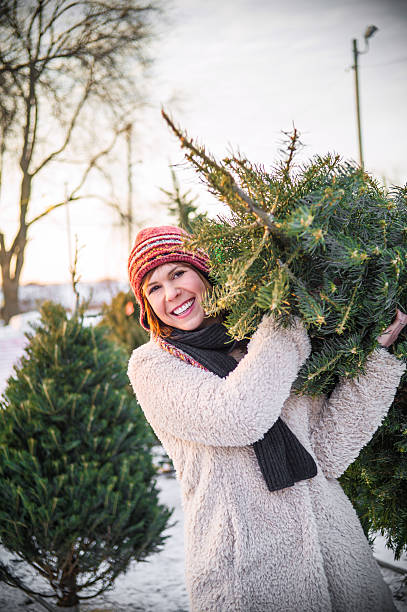 istock woman carrying christmas tree 462285527
