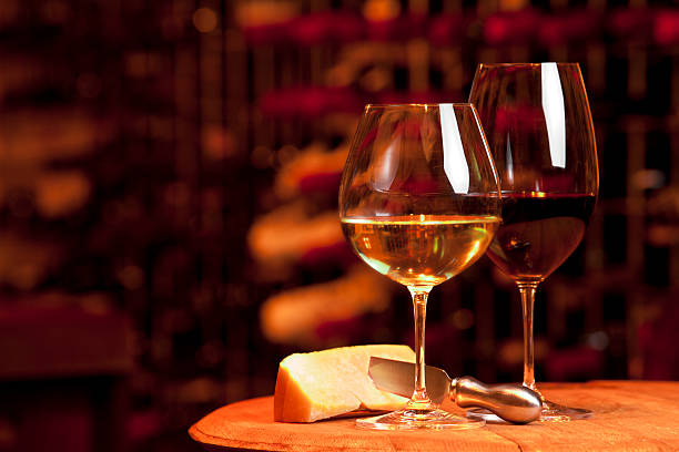 due bicchieri di vino in piedi su un tagliere per formaggi - wine cheese food cellar foto e immagini stock