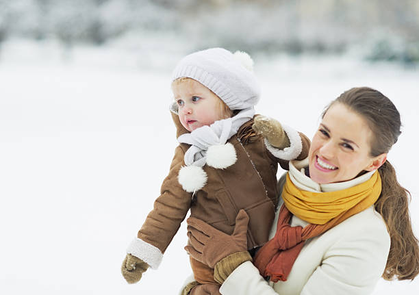 istock Mother holding baby looking on copy space in winter park 462307489