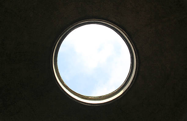 Architectural detail of beautifully decorated blue wooden circle window on a building with facade painted in white