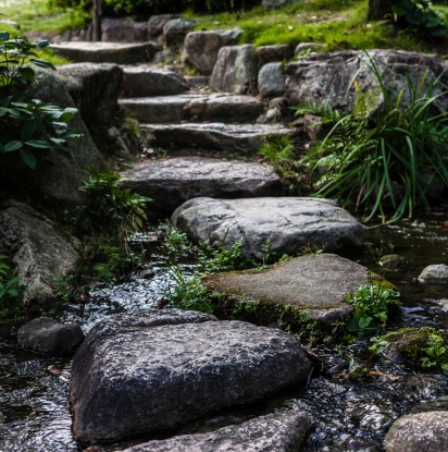 Zen stone pathway over a stream in a traditional Japanese garden somewhere in Tokyo