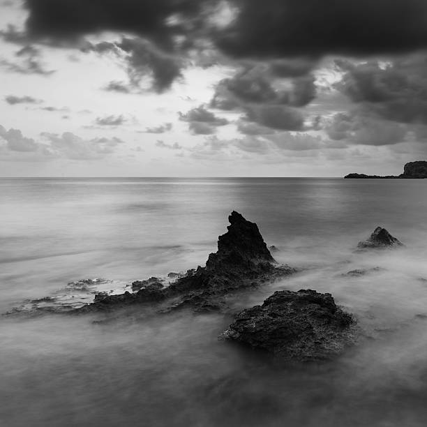 восход солнца над скалистыми береговая линия в черно-белом - black and white landscape square long exposure стоковые фото и изображения