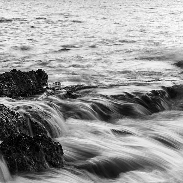 на океан с течет через скалистые берега в черно-белом - black and white landscape square long exposure стоковые фото и изображения