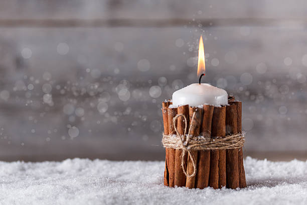 Christmas candle wrapped in cinnamon sticks in the snow stock photo