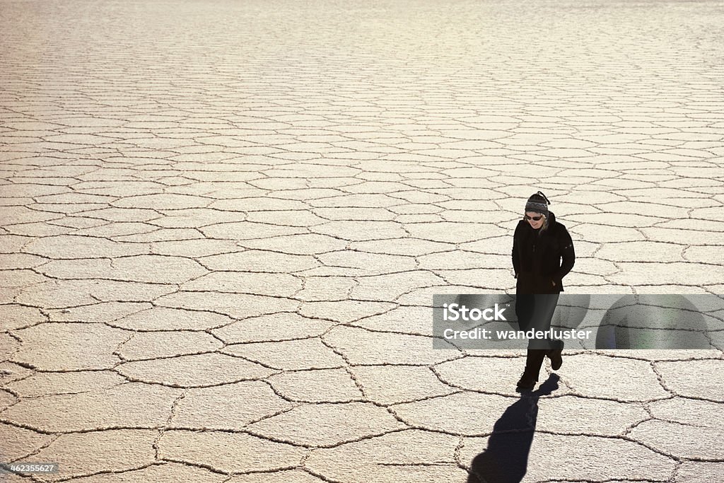 woman walking across salt flats Woman walking across hexagonal patterns on salt flats in late afternoon, Salar de Uyuni, Bolivia, South America Hexagon Stock Photo