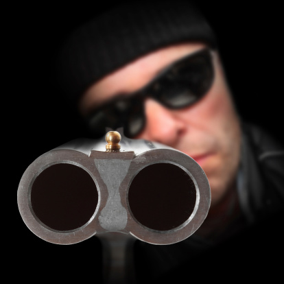 Gangster with shotgun aimed at you. Gun control concept. Close up with shallow DOF.