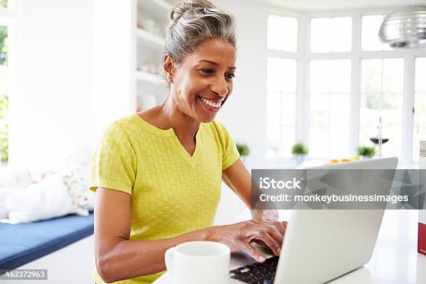 African American Woman Using Laptop In Kitchen At Home Stock Photo - Download Image Now