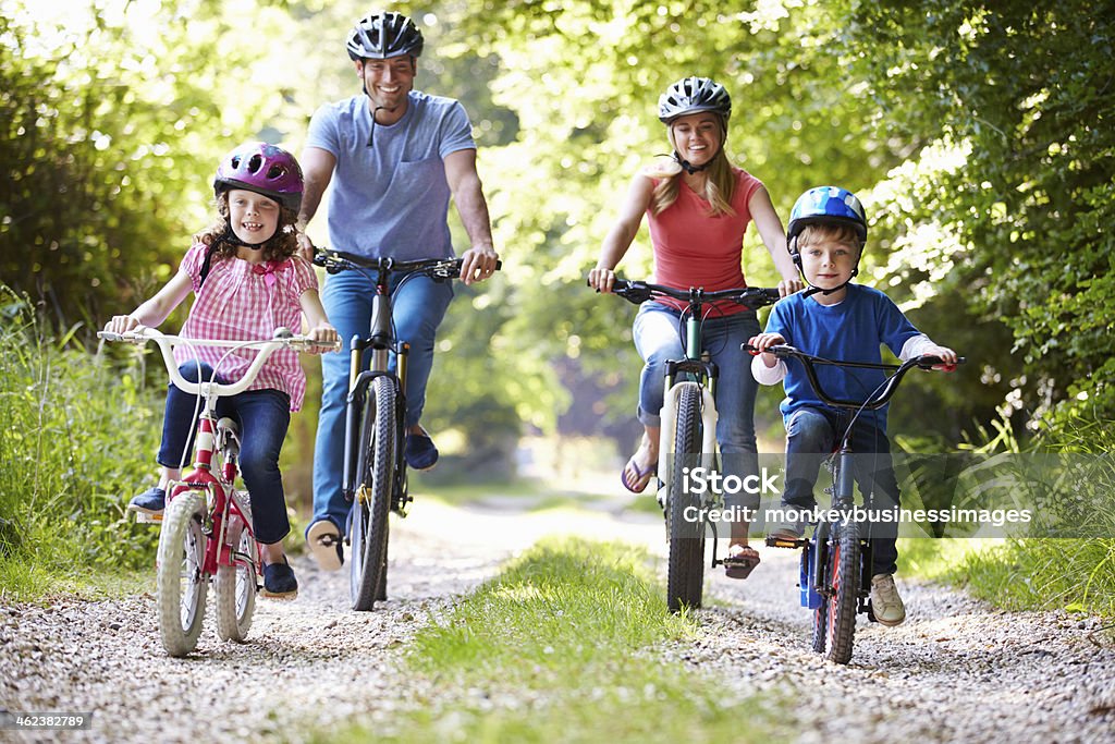 Familia de cuatro con las bicicletas en el camino de grava riding - Foto de stock de Familia libre de derechos