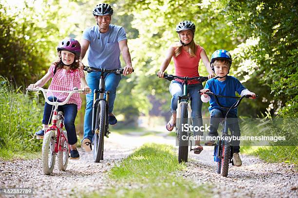 Familia De Cuatro Con Las Bicicletas En El Camino De Grava Riding Foto de stock y más banco de imágenes de Familia