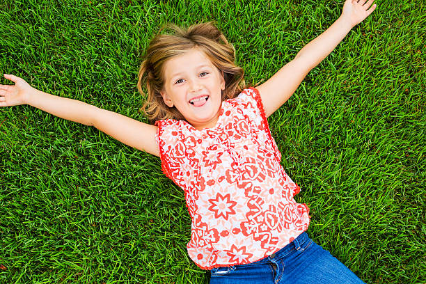 istock Smiling little girl lying on green grass 462386605
