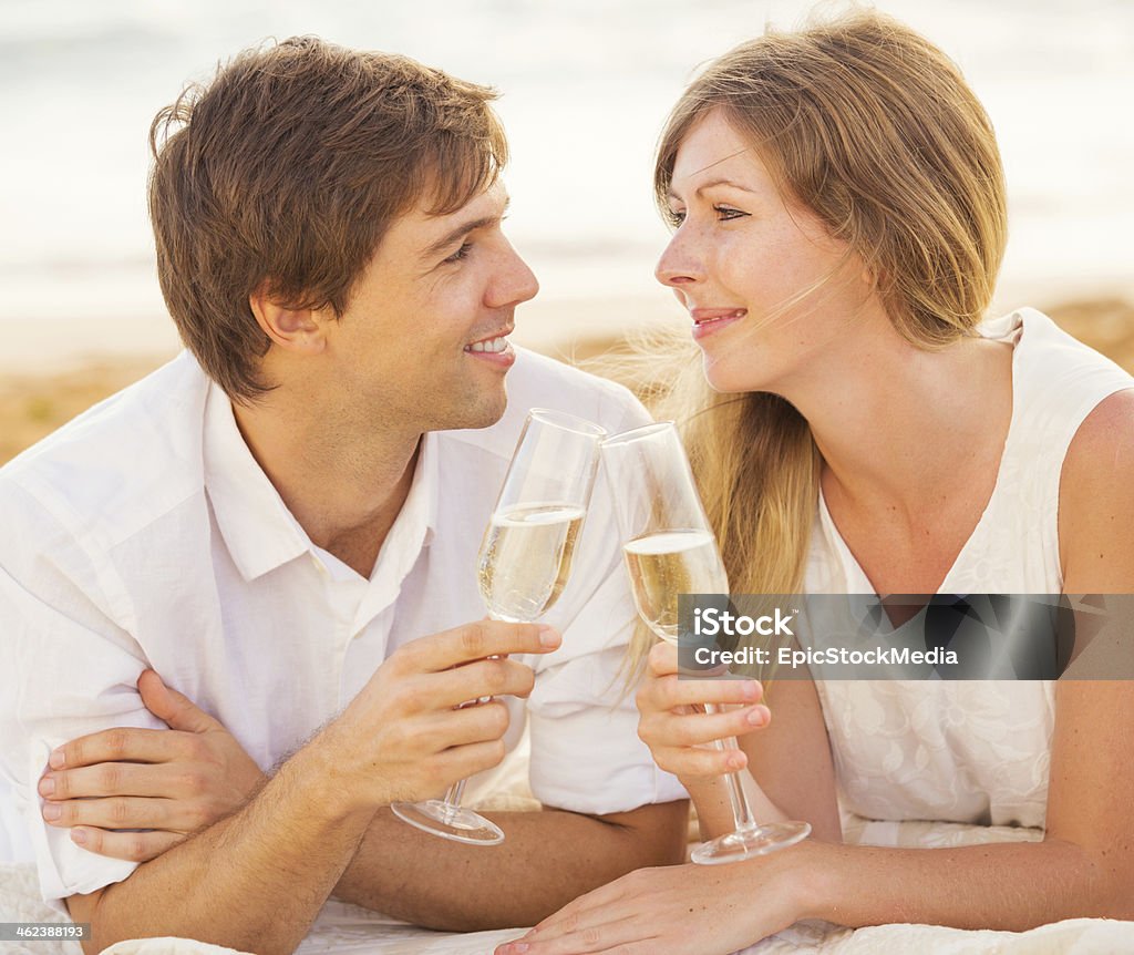 Honeymoon concept, Man and Woman in love Honeymoon concept, Man and Woman in love, Couple enjoying glass of champagne on tropical beach at sunset Adult Stock Photo