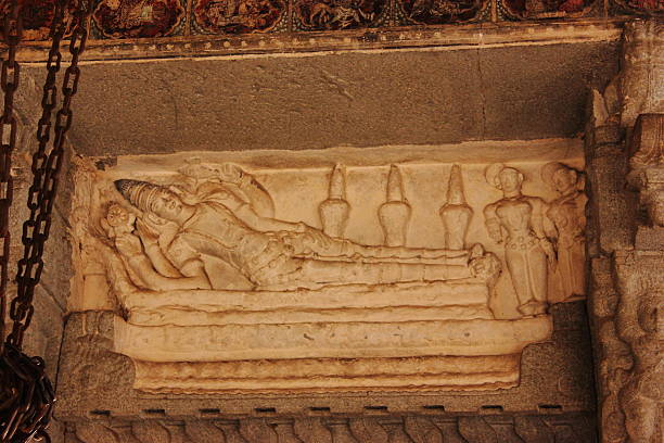 Hugh stone carved ancient sculpture of hindu God Vishnu in lying position in Virupaksha temple in Hampi, Karnataka, India.