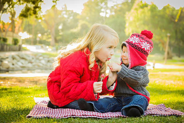 menina com irmão vestindo casacos e chapéus ao ar livre - winter child coat baby girls - fotografias e filmes do acervo