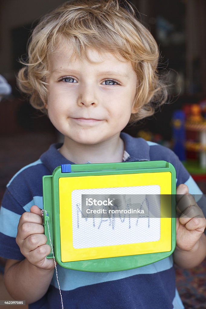 Little toddler boy with painting board writes his first word Little toddler boy with painting board writes his first word mama 12-17 Months Stock Photo