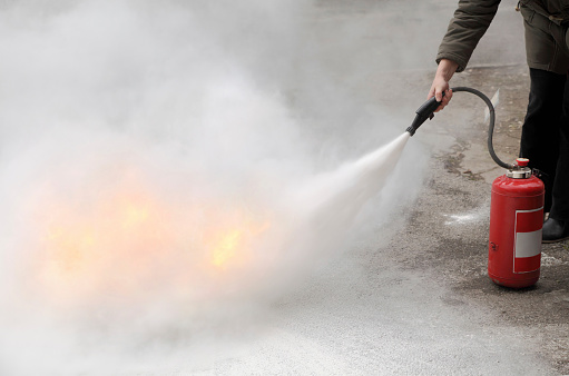 A woman demonstrating how to use a fire extinguisher